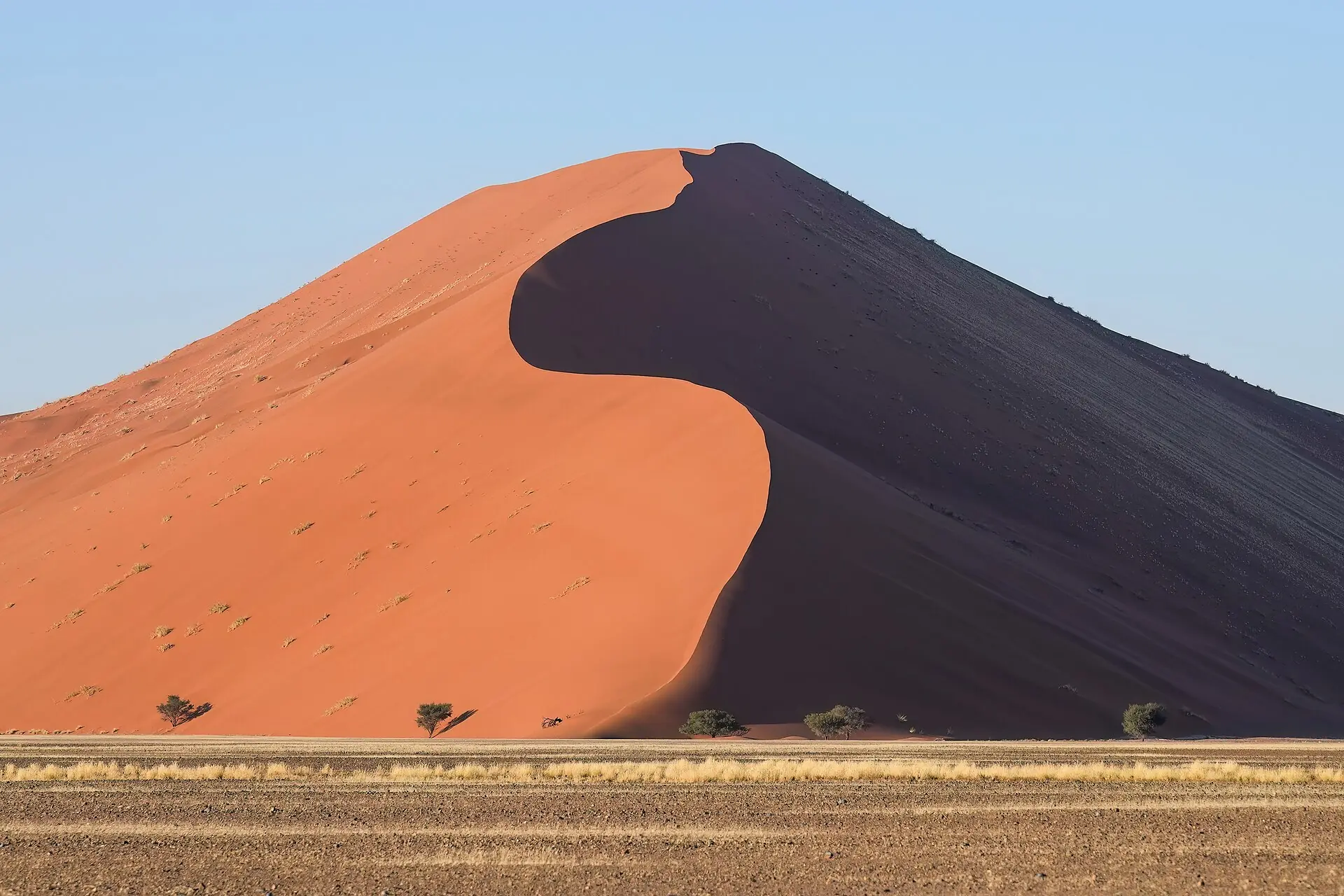 A colossal sand dune at sunrise, knife-edge ridge